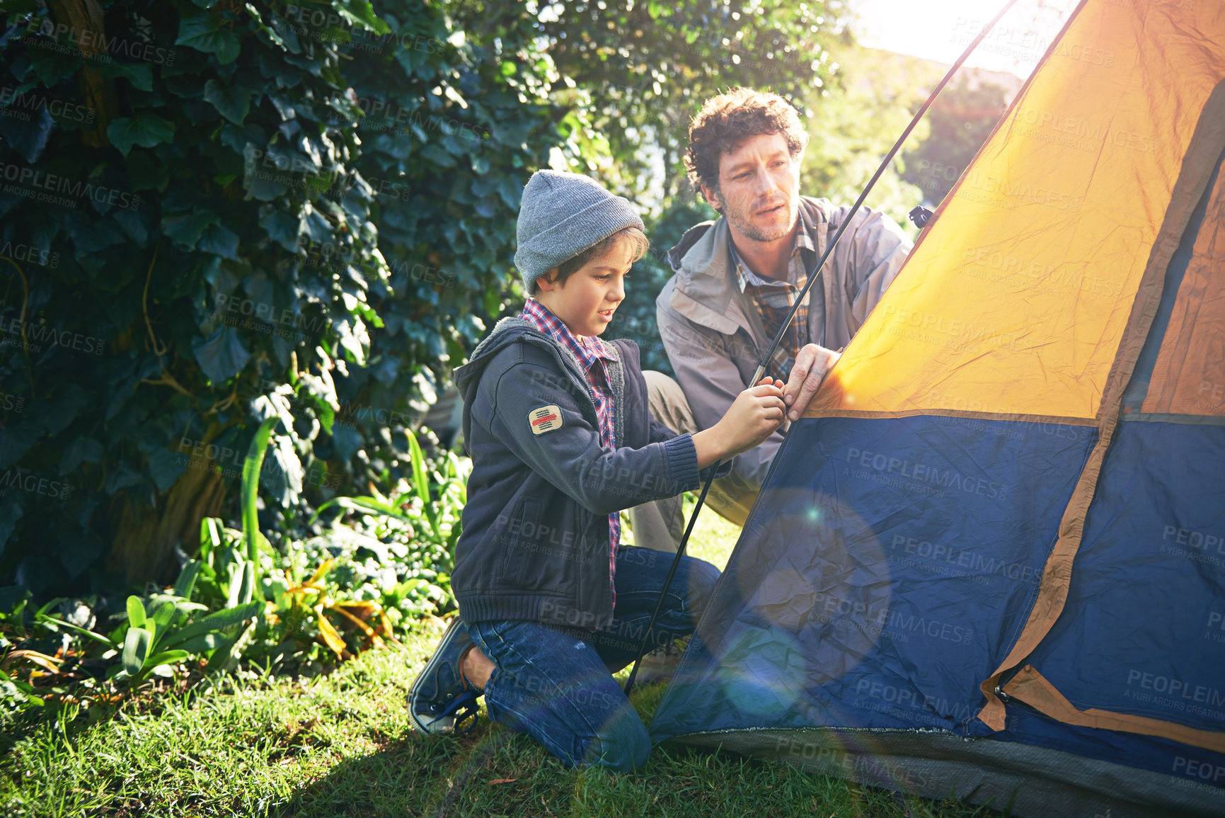 Buy stock photo Shot of a father and his young son putting up their tent