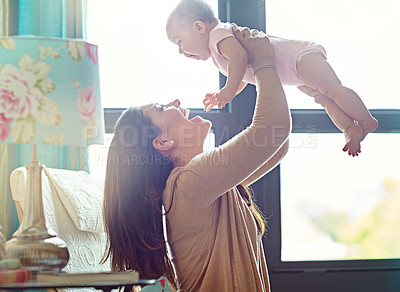 Buy stock photo Shot of a mother holding her baby daughter up in the air