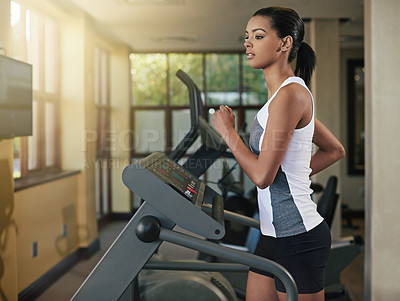 Buy stock photo Shot of a young woman exercising on a treadmill at the gym
