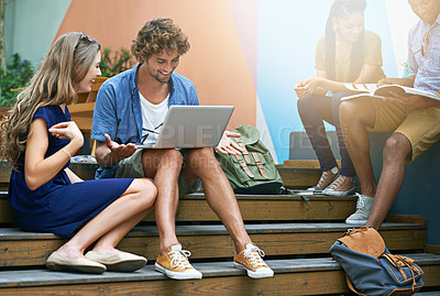 Buy stock photo Shot of two students using a laptop on campus