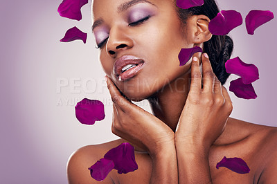 Buy stock photo Flower, petal and black woman in studio for makeup, beauty or wellness on purple background. Floral, skin and Africa model with soft cosmetics, shine or organic transformation with lavender aesthetic