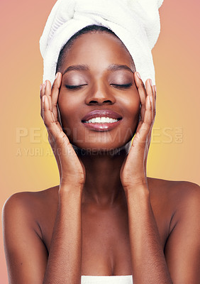 Buy stock photo Hair towel, black woman and beauty in studio with skincare, wellness or body care on orange background. Makeup, cleaning or hands on face of African female model with cosmetic, shine or glow results