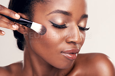 Buy stock photo Studio shot of a beautiful young woman applying blush with a makeup brush