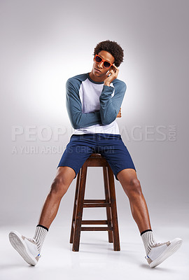 Buy stock photo Cool guy, shades and studio chair for trendy fashion, hipster style and creative aesthetic indoor. African man or handsome fashionista and sitting on stool with confidence in clothes and sneakers 