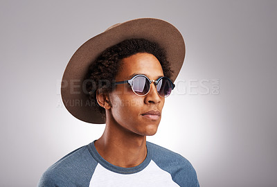 Buy stock photo Studio shot of a young man wearing sunglasses and a hat against a gray background