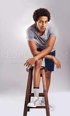 Buy stock photo Fashion, stool and portrait of black man in studio with casual, trendy and stylish outfit. Serious, chair and full body of African male person with cool style and sneakers isolated by gray background