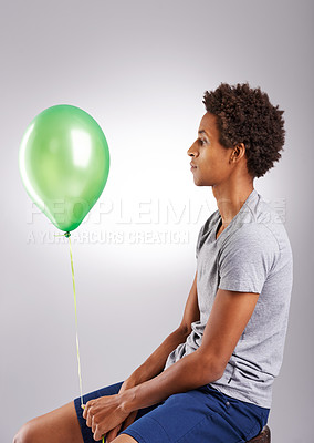 Buy stock photo Black man, balloon and thinking in studio for mental health with sad, green and unhappy. Male person, problem and sphere by grey background for anxiety with frustrated, negative attitude and moody