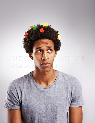 Buy stock photo Shot of a young man with colorful paper in his hair against a gray background