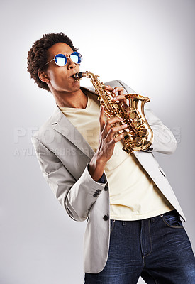 Buy stock photo Fashion, sunglasses and man with saxophone in studio with classy, trendy and stylish outfit. Style, handsome and male musician playing brass musical instrument for jazz isolated by gray background.