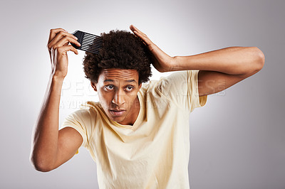 Buy stock photo Studio shot of a young man combing his afro against a gray background