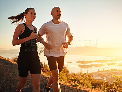 Buy stock photo Shot of a young couple running together along a road
