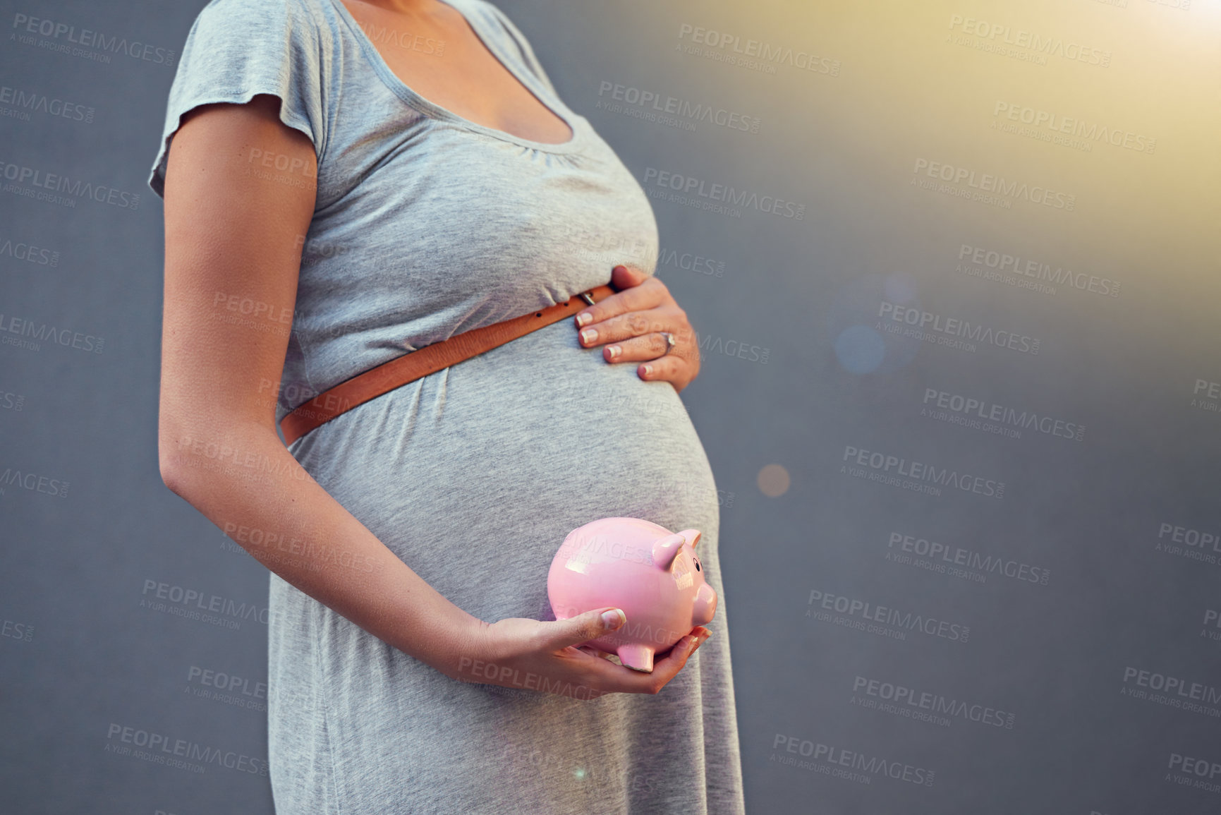 Buy stock photo Cropped shot of a pregnant woman holding a piggybank against a gray background