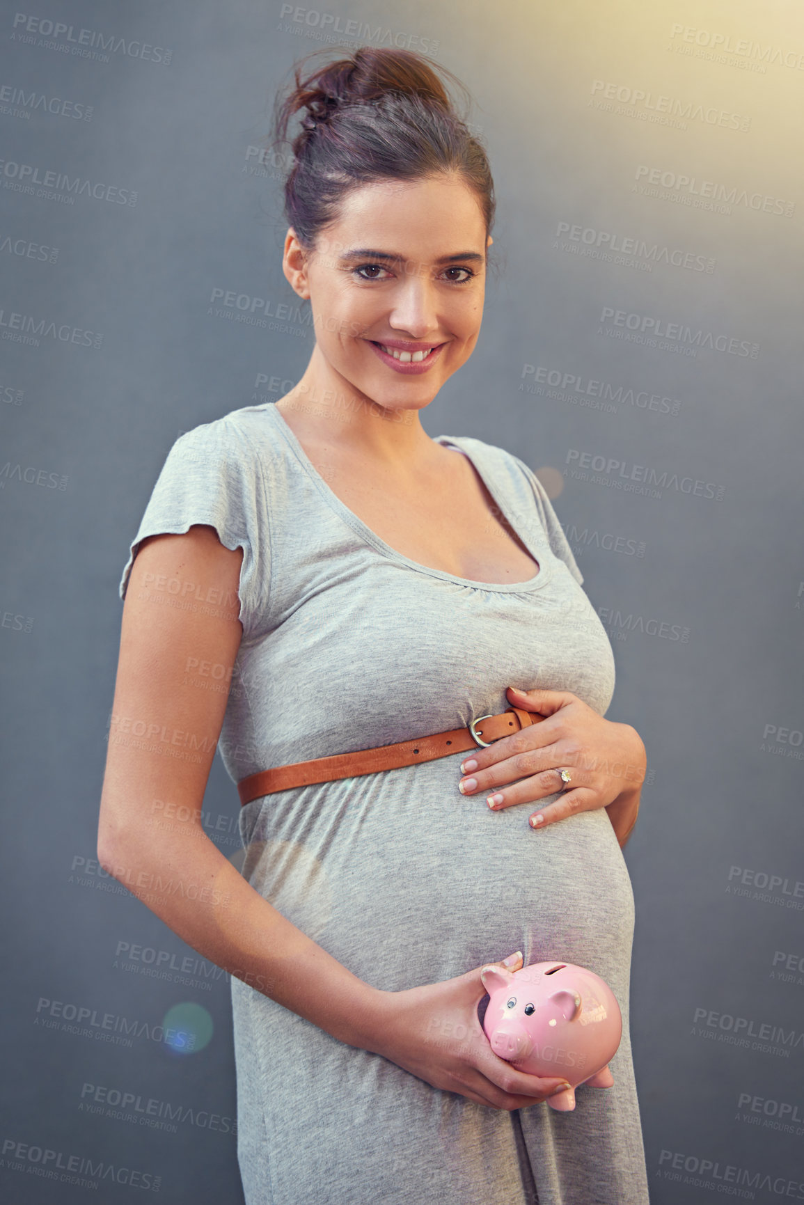 Buy stock photo Cropped shot of a pregnant woman holding a piggybank against a gray background