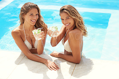 Buy stock photo Portrait of twin sisters relaxing with drinks in a swimming pool