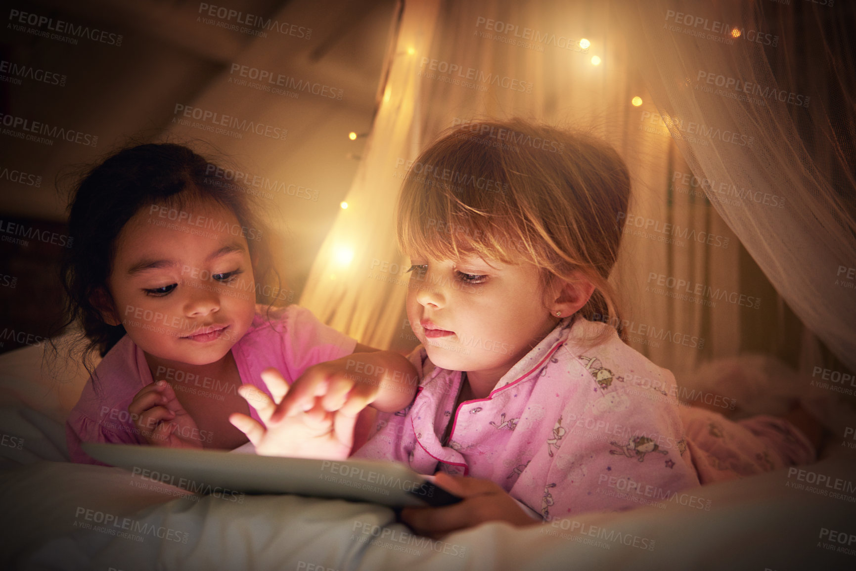 Buy stock photo Shot of two little girl using a digital tablet at their sleepover