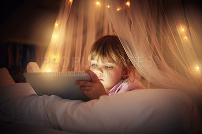 Buy stock photo A young girl lying on her bed while using a digital tablet