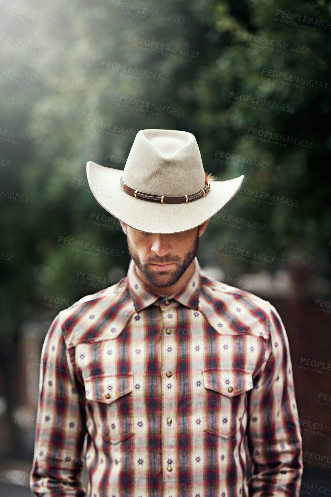 Buy stock photo Shot of a handsome cowboy wearing a check shirt and stetson