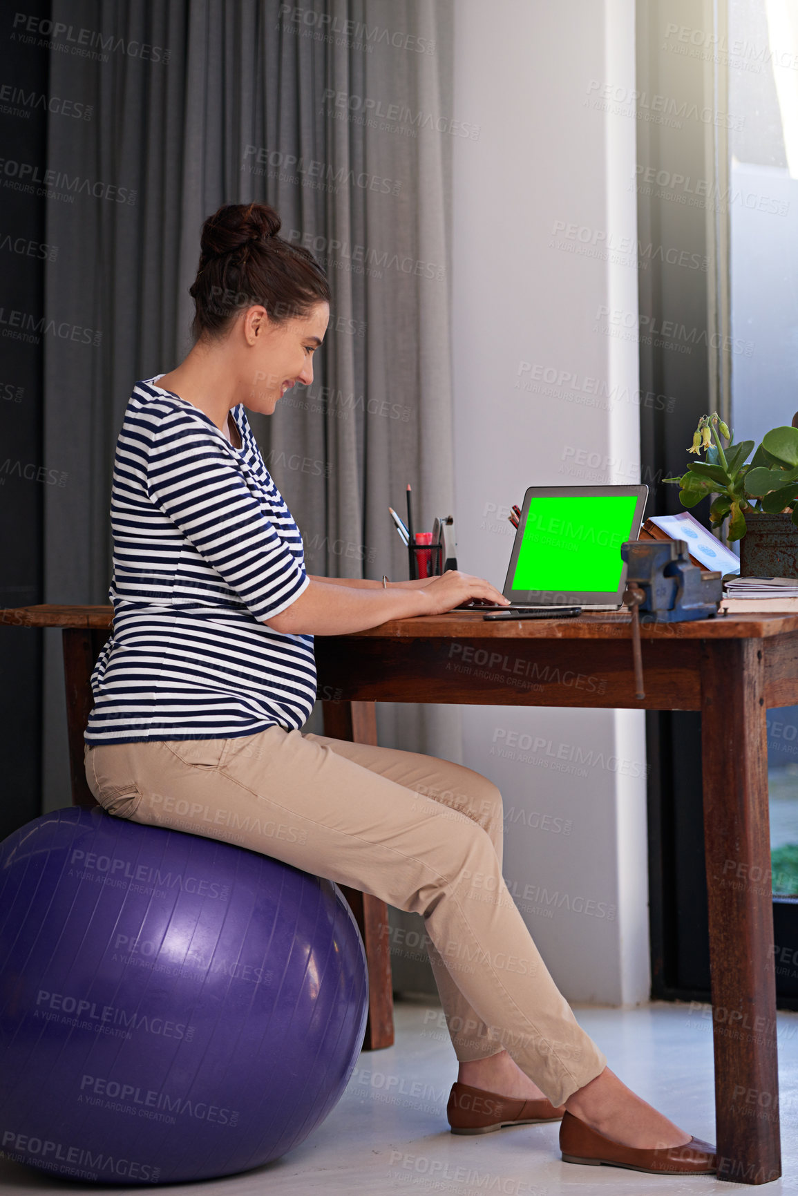 Buy stock photo Full length shot of a young pregnant woman working on a laptop on her office