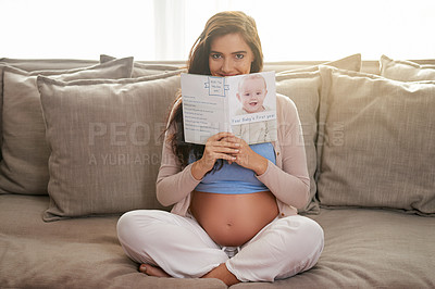 Buy stock photo Shot of a young pregnant woman reading a baby book at home