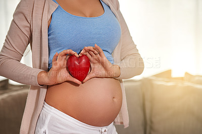 Buy stock photo Pregnant woman, belly and heart at home for healthy maternity, growing family or developmental support. Lady, in living room and excited for motherhood, love or bonding and caring for unborn child