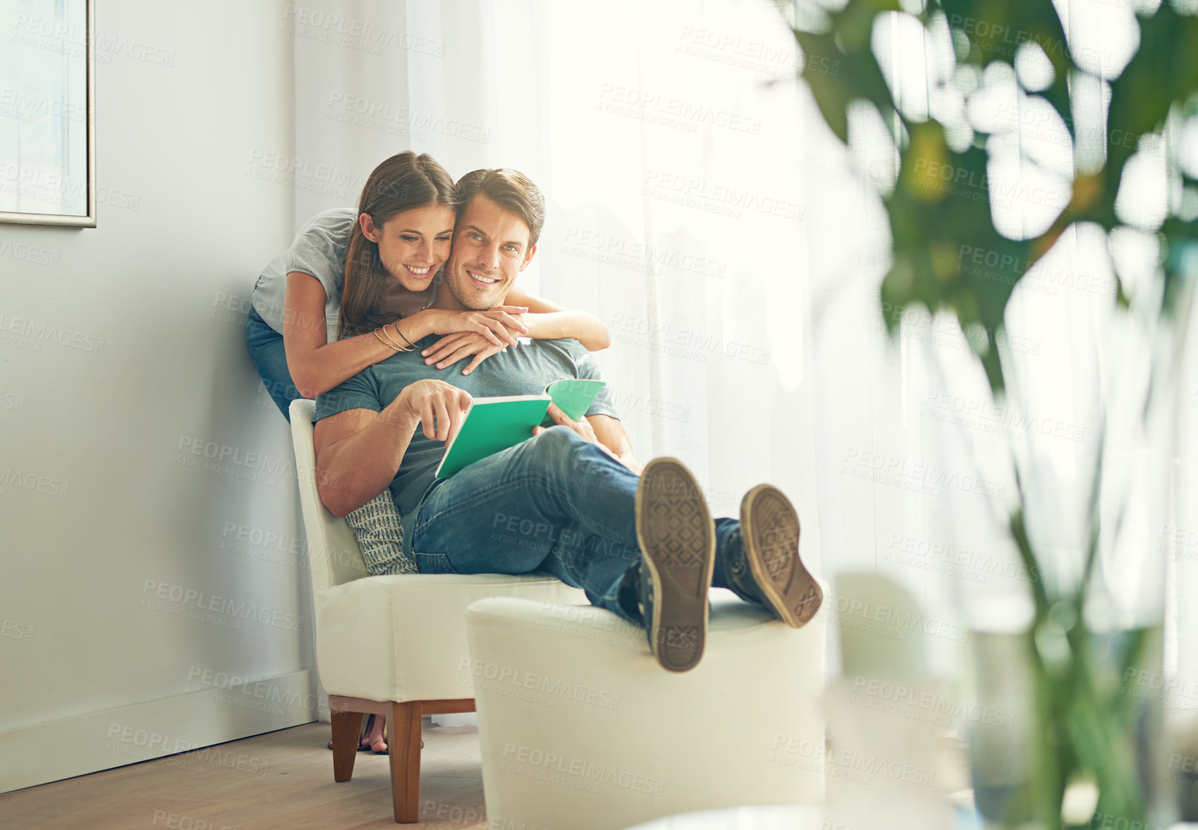 Buy stock photo Couple, embrace and book in home, love and chair to relax in lounge on sofa for learning. Man, woman and romance while happy, smile and reading for entertainment and together in living room with hug