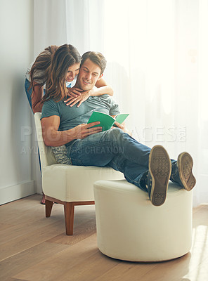 Buy stock photo Couple, happy and book in home, love and chair to relax and minimalist interior for learning. Man, woman and romance while embrace, smile and reading for entertainment and together in living room