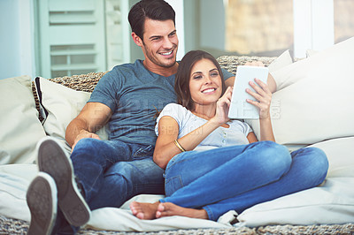 Buy stock photo Happy couple, relax and sofa with tablet to watch movie, social media or entertainment at home. Man and woman lying with smile on technology for streaming subscription, series or show in living room