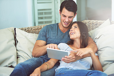 Buy stock photo Happy couple, hug and sofa with tablet for movie, social media or entertainment at home. Man and woman lying in relax with smile on technology for online streaming, series or show in living room