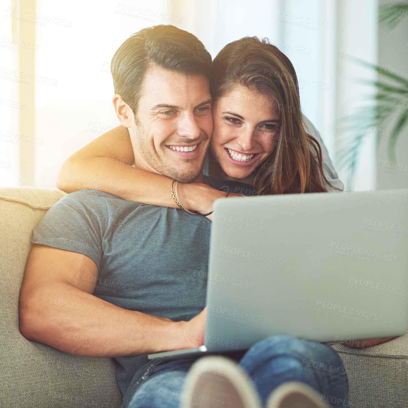Buy stock photo Shot of an affectionate young couple using a laptop at home