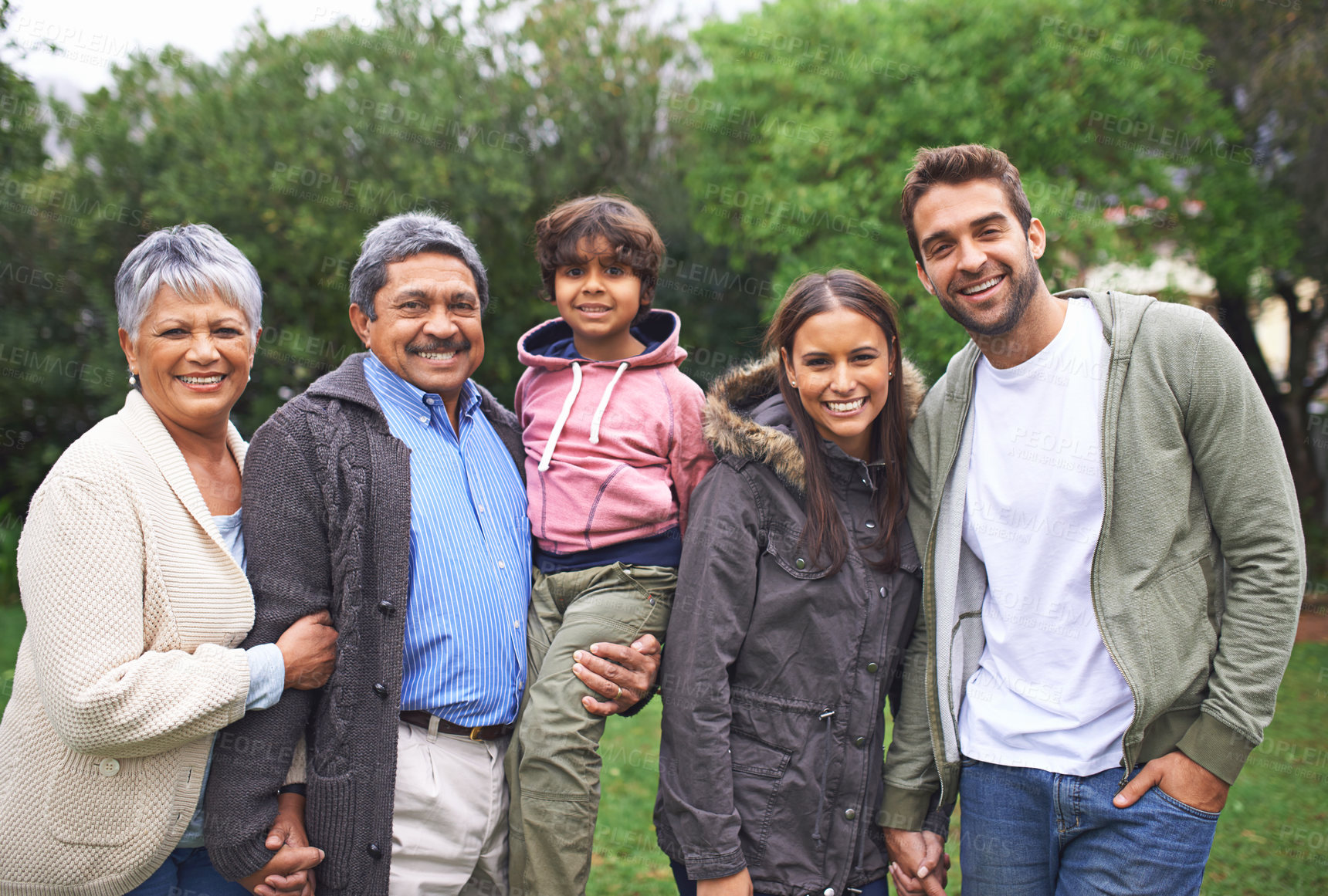Buy stock photo Portrait, smile and big family in nature outdoor for bonding, relationship and holding hands at backyard. Face, park and child with parents, grandparents and mom with interracial father in garden