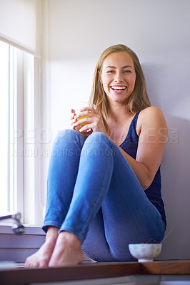 Buy stock photo Shot of a young woman having juice while sitting in her kitchen