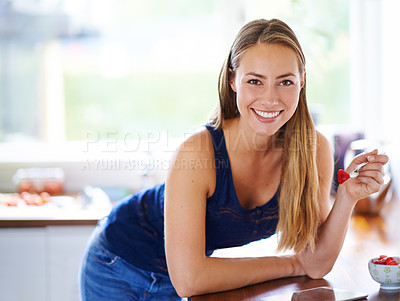 Buy stock photo Portrait of a young woman eating a bowl of strawberries at home