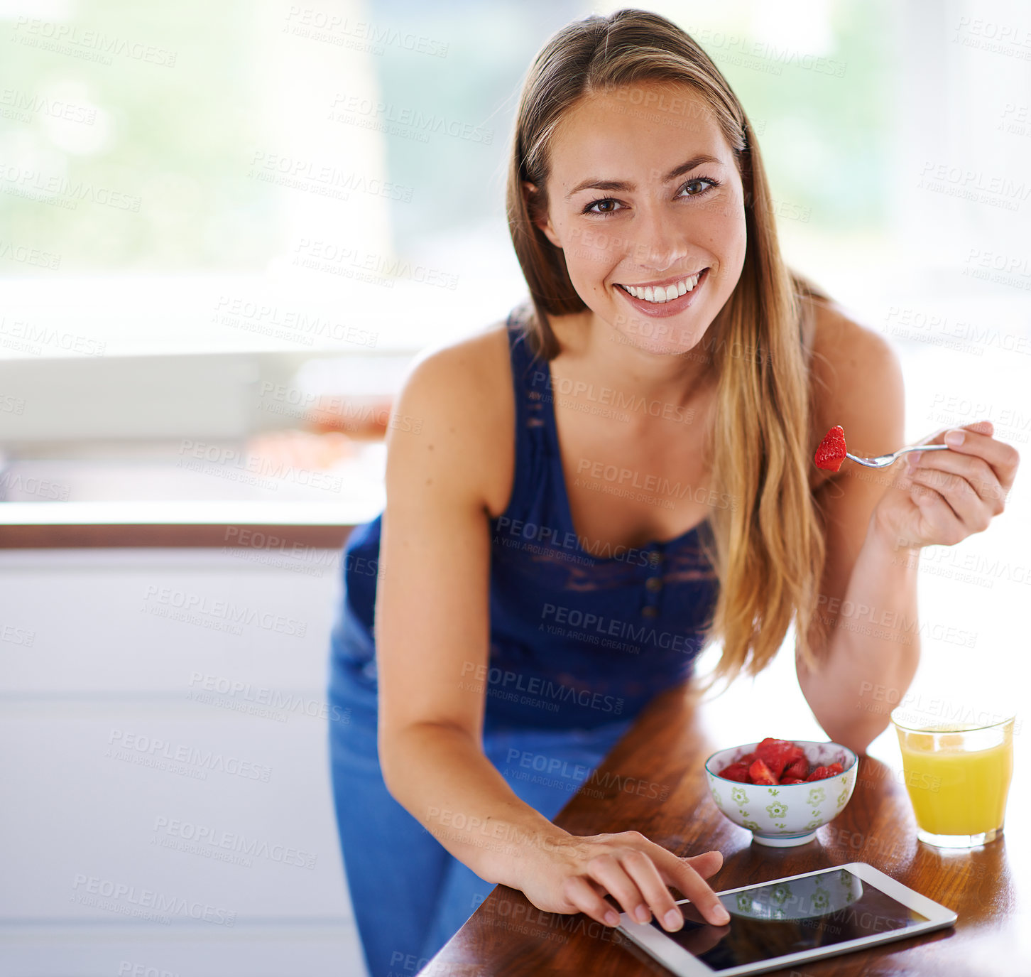 Buy stock photo Shot of a woman using her digital tablet while having a bowl of strawberries