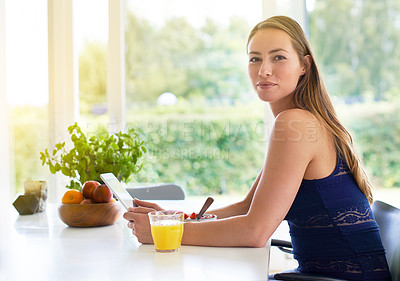 Buy stock photo Shot of a woman using her digital tablet while having a bowl of strawberries