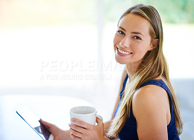 Buy stock photo Shot of a young woman using her digital tablet while having cup of coffee
