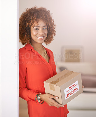 Buy stock photo Portrait of a young woman holding a cardboard box inside her home