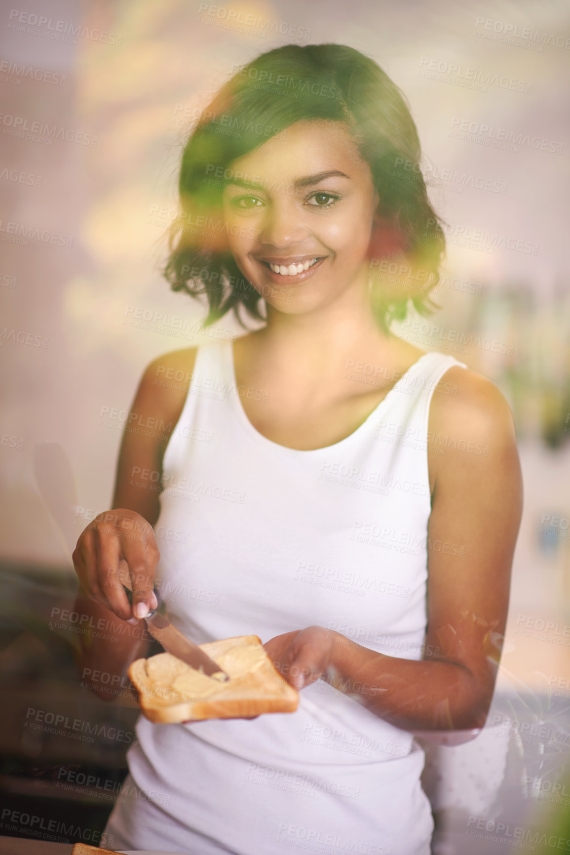 Buy stock photo Shot of a young woman spreading butter onto toast