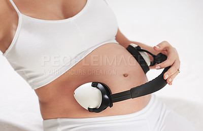 Buy stock photo Woman, pregnant and headphones on stomach with music in studio for calming, parent or listening. Mother, audio and belly for soothing baby in womb for maternity bonding in home, streaming or relax