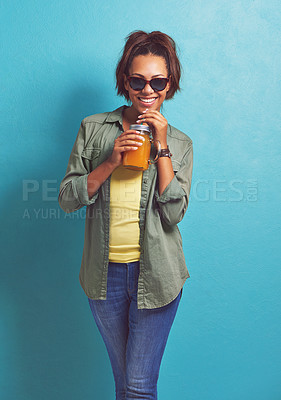 Buy stock photo Happy woman, portrait and sunglasses with orange juice for vitamin C or summer fashion on a blue studio background. Female person, brunette or model with smile for citrus drink or fresh beverage
