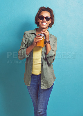 Buy stock photo Happy woman, portrait and sunglasses with orange juice in fashion for vitamin C or diet on a blue studio background. Female person, brunette or model with smile for citrus drink or fresh beverage