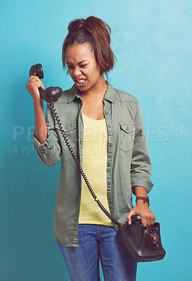 Buy stock photo Shot of a young woman looking irritatedly at a telephone
