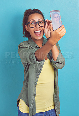 Buy stock photo Happy woman, nerd and glasses with selfie for picture, memory or review on a blue studio background. Young female person, model or geek with smile or fashion for social media, moment or photography