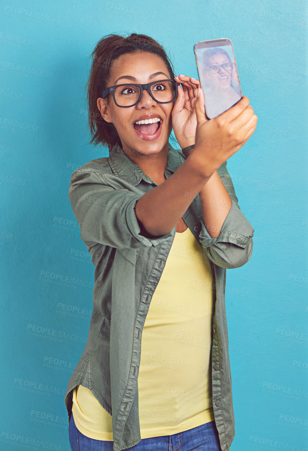 Buy stock photo Shot of a young woman taking a selfie against a blue background