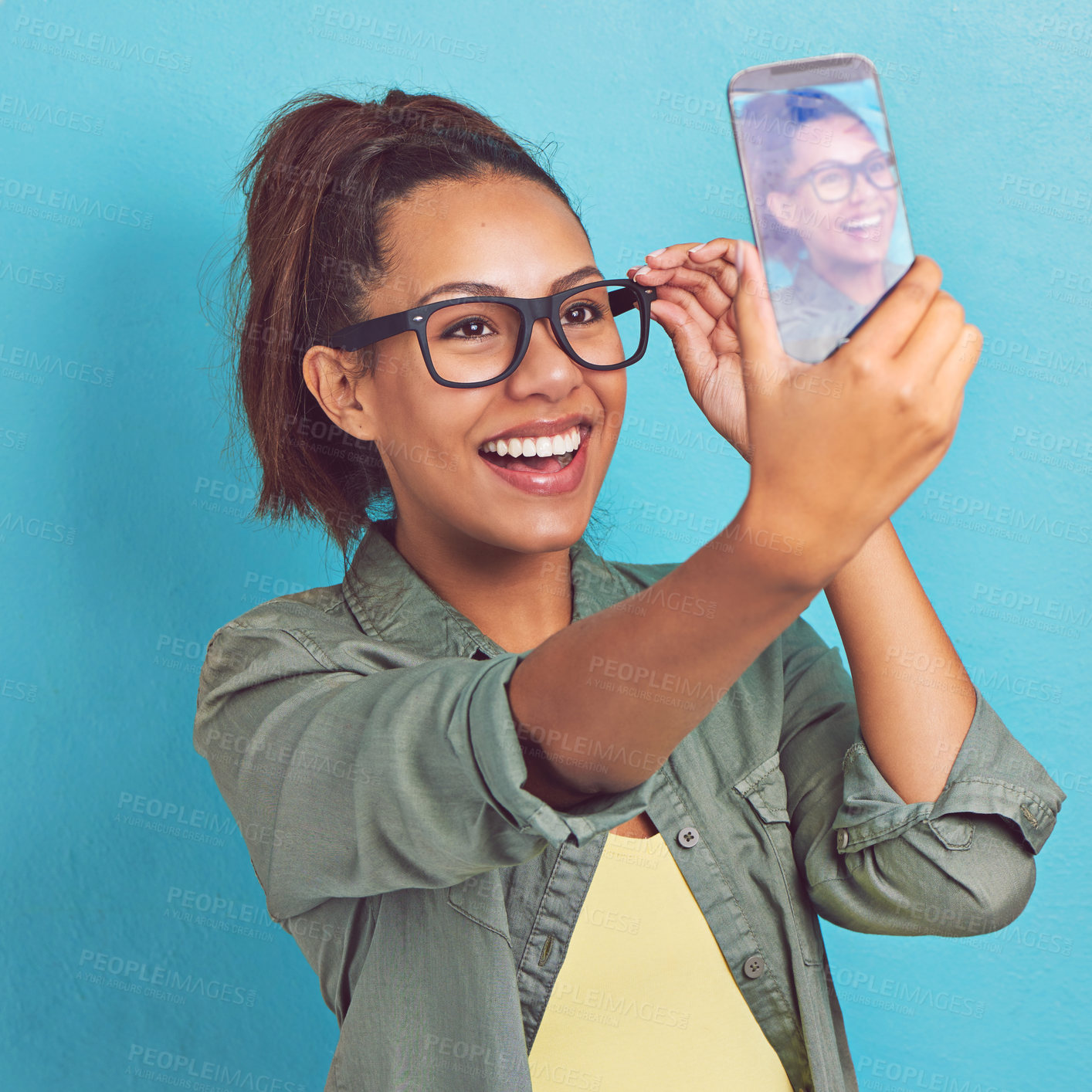 Buy stock photo Happy woman, geek and glasses with selfie for picture, memory or review on a blue studio background. Young female person, model or nerd with smile or fashion for social media, moment or photography