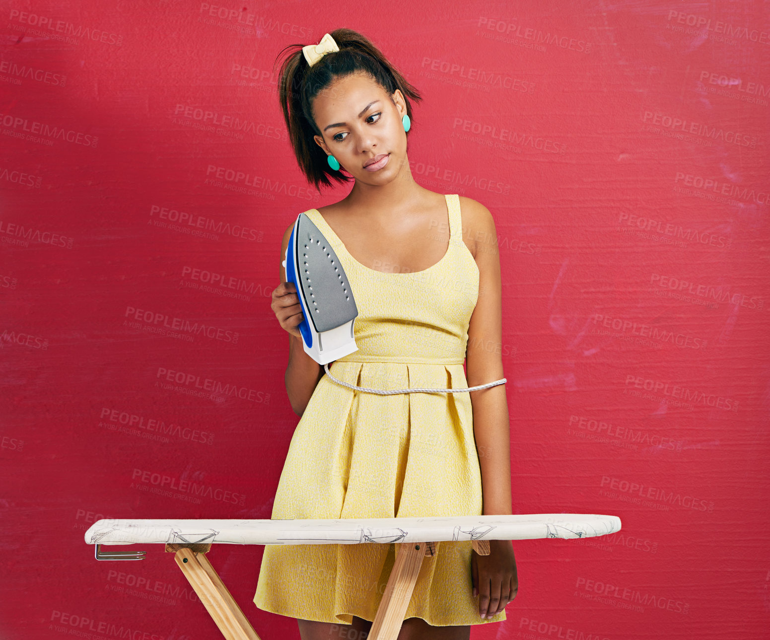 Buy stock photo Studio shot of a young woman doing the ironing against a red background