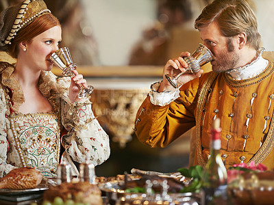 Buy stock photo Couple, noble and wine with luxury, feast and renaissance dining table at royal home. King, queen and food with wealth, rich meal and palace or manor for romance with historical chalice and drink