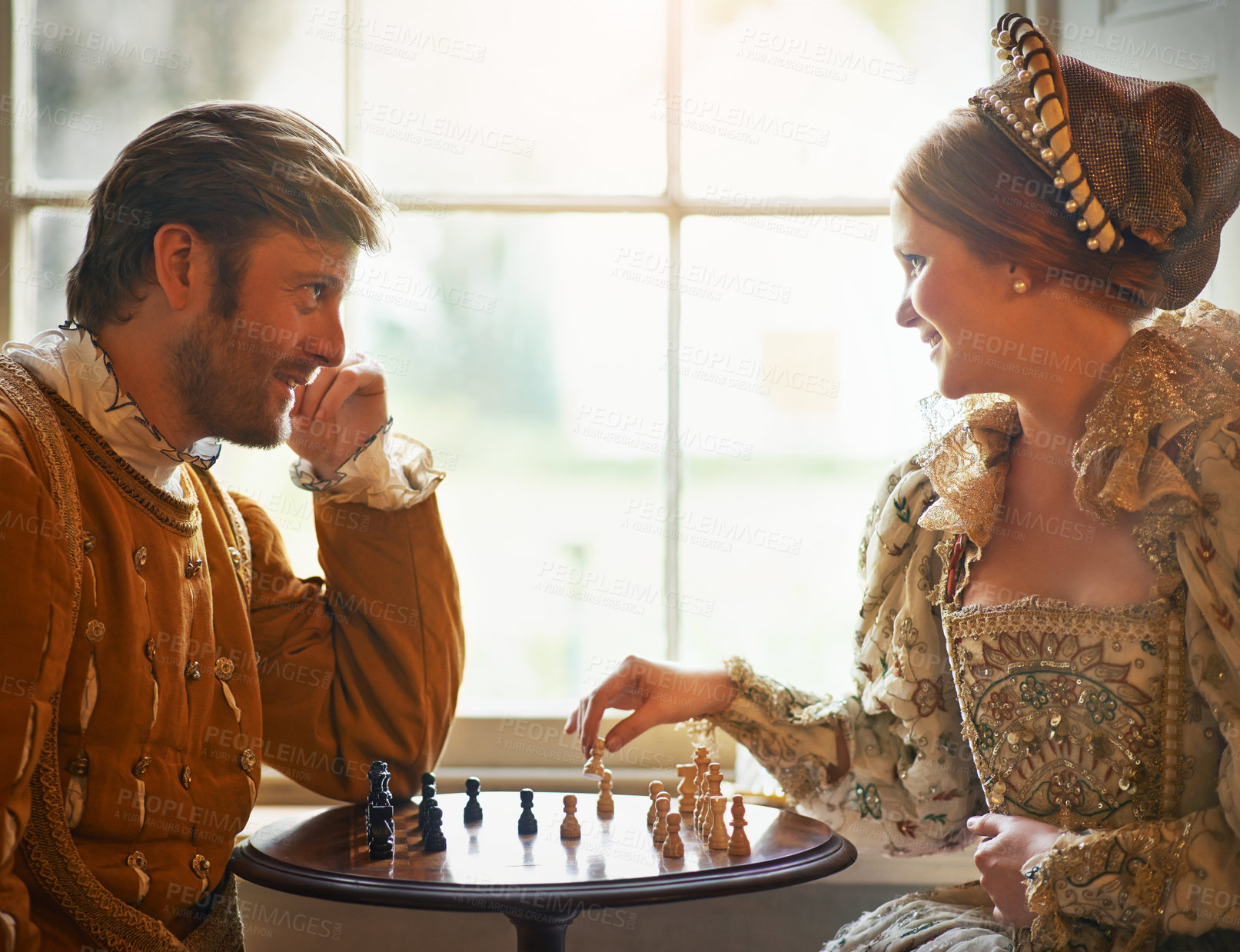 Buy stock photo Renaissance, couple and chess at home with smile, vintage and medieval costume in a palace. Window, luxury and queen together with smile from strategy game and talking while playing with love