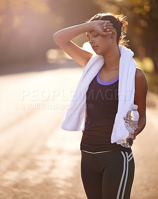 Buy stock photo Shot of a woman wiping away the sweat after some intense outdoor training