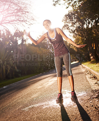 Buy stock photo Shot of a young woman pouring cold water over her head after an intense workout