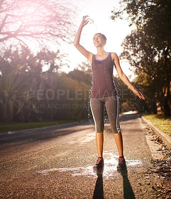 Buy stock photo Shot of a young woman pouring cold water over her head after an intense workout
